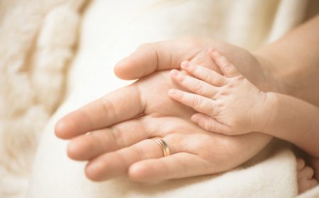 Newborn child hand. Closeup of baby hand into parents hands. Family, maternity and birth concept